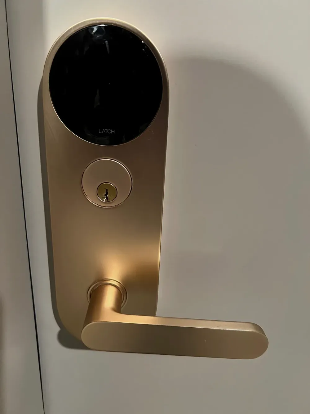 Gold smart lever lock with a key cylinder on a white door