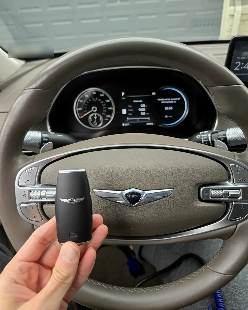 New Genesis smart key held at the steering wheel by a locksmith serving Garden City, NY
