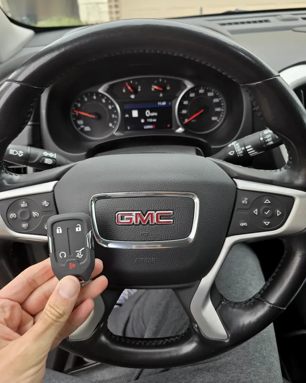 New GMC smart key with remote start held at the steering wheel by a locksmith serving Woodmere, NY