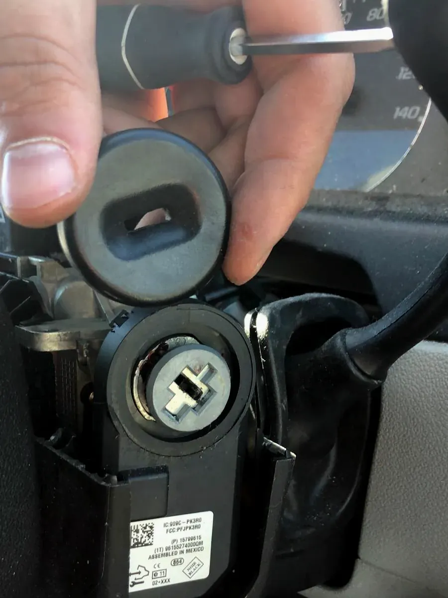 Car ignition cylinder exposed during a repair, with a tool in hand