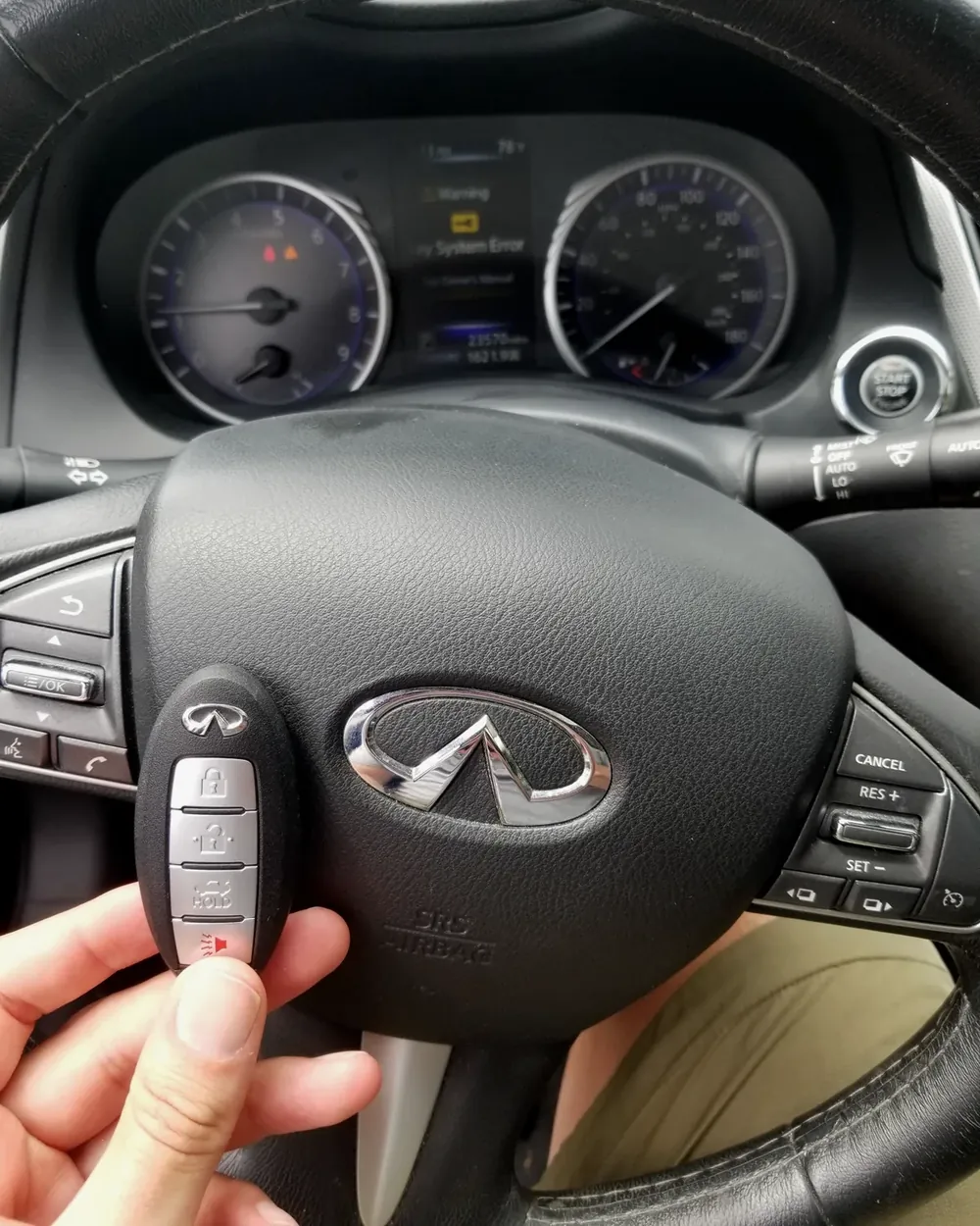 New Infiniti smart key held at the steering wheel by a locksmith serving Malverne, NY