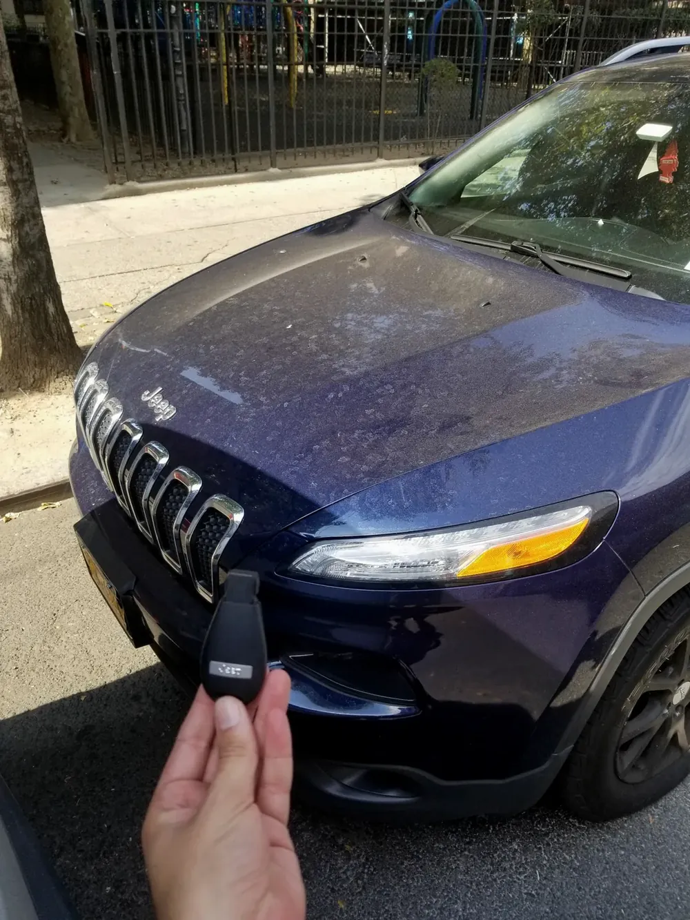 New Jeep Cherokee key held in front of the car on a street