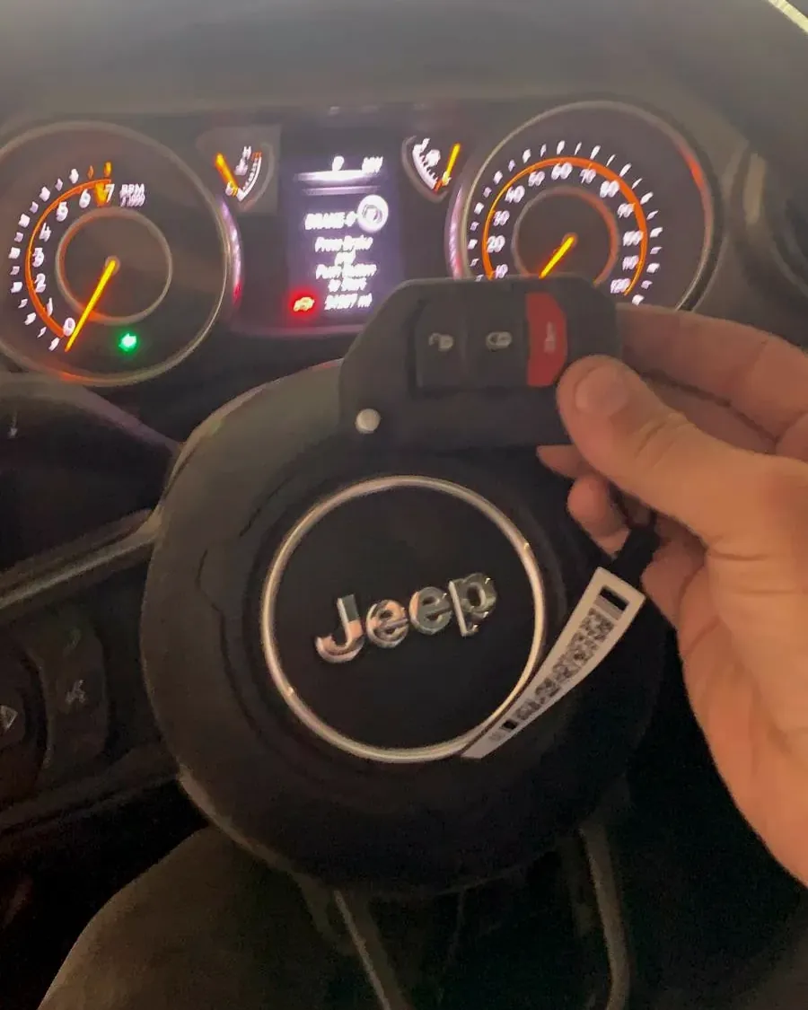 New Jeep flip key with its tag held in front of the steering wheel