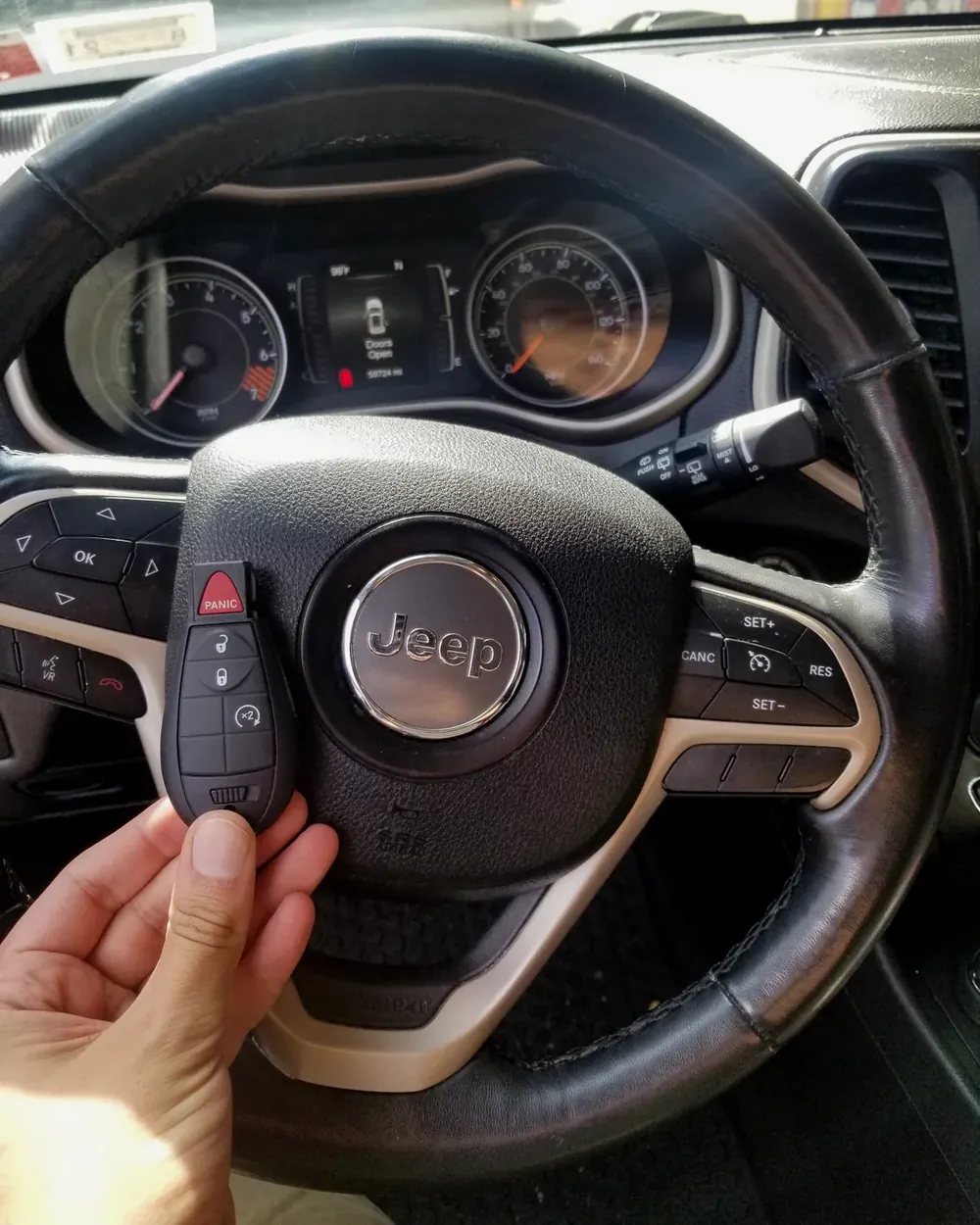 New Jeep smart key held at the steering wheel by a locksmith serving Lawrence, NY