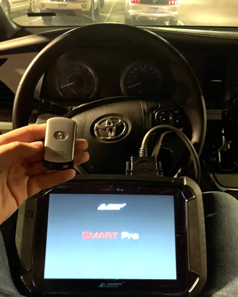 Toyota smart key being programmed with a key programming tool inside the car