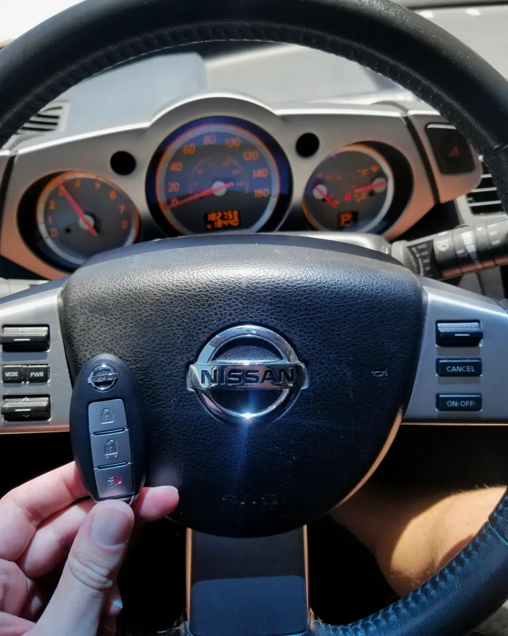 New Nissan smart key held at the steering wheel by a locksmith serving East Rockaway, NY