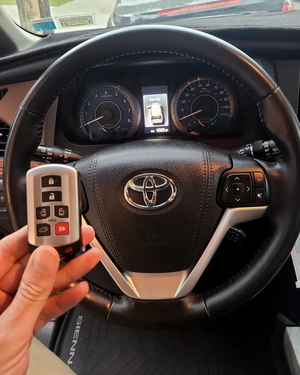New Toyota smart key held at the steering wheel by a locksmith serving Merrick, NY