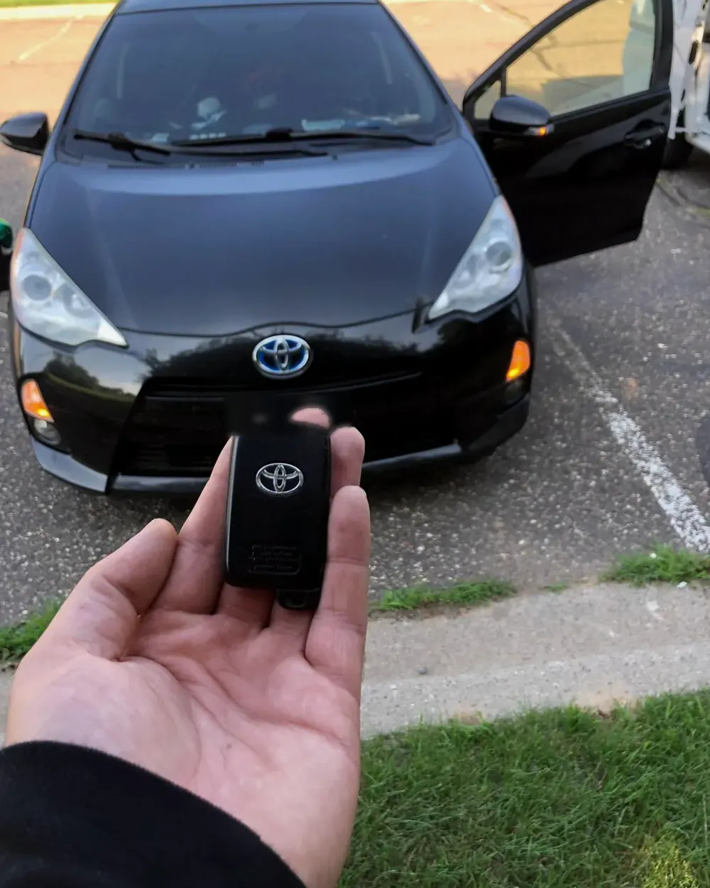 New Toyota smart key held in front of a black Toyota in a parking lot
