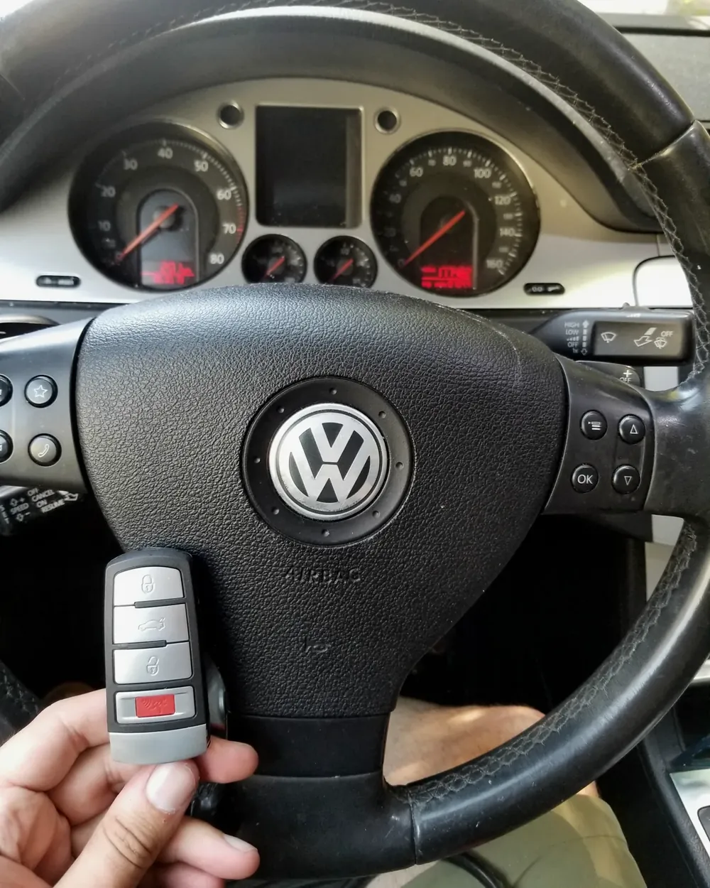 New Volkswagen smart key held at the steering wheel by a locksmith serving Hewlett, NY
