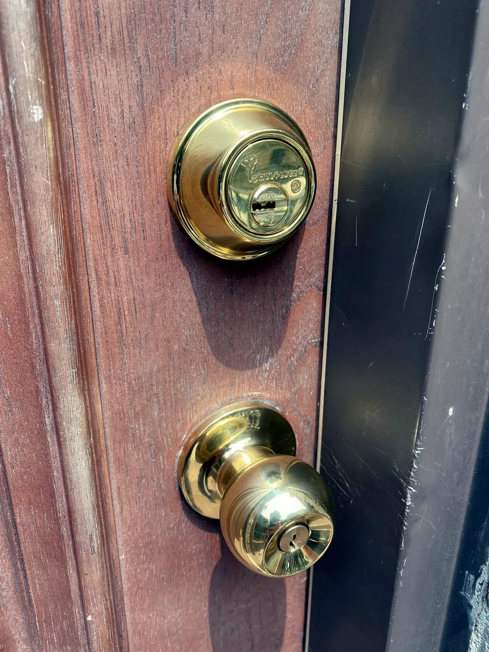 Cerrojo y cerradura de pomo nuevos de latón instalados en una puerta de madera