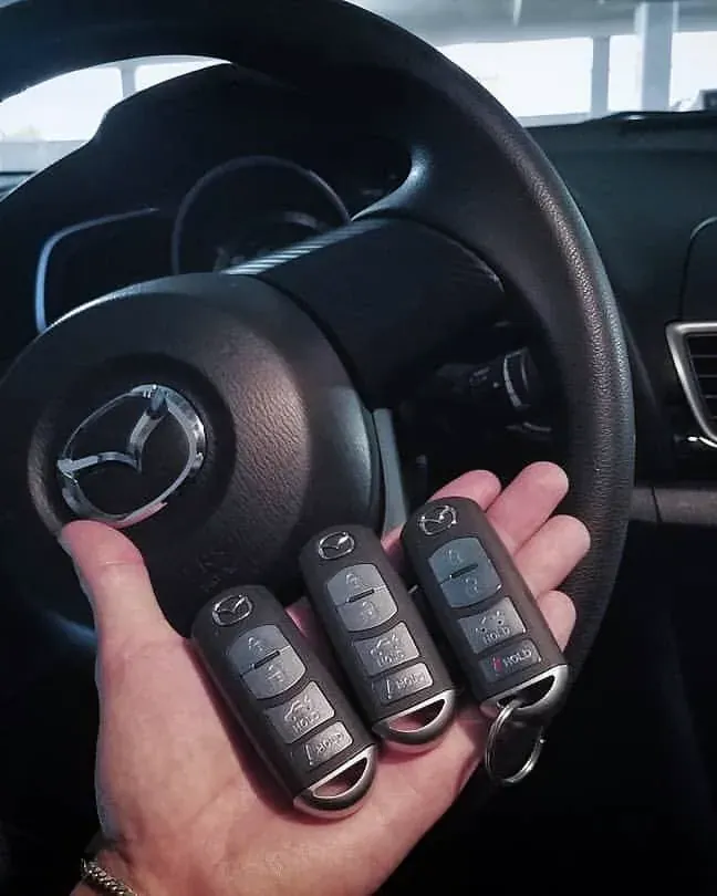 Tres llaves nuevas con control para un carro Mazda frente al volante