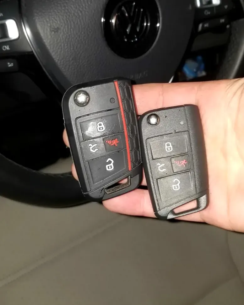 Original and new Volkswagen flip keys held next to the steering wheel