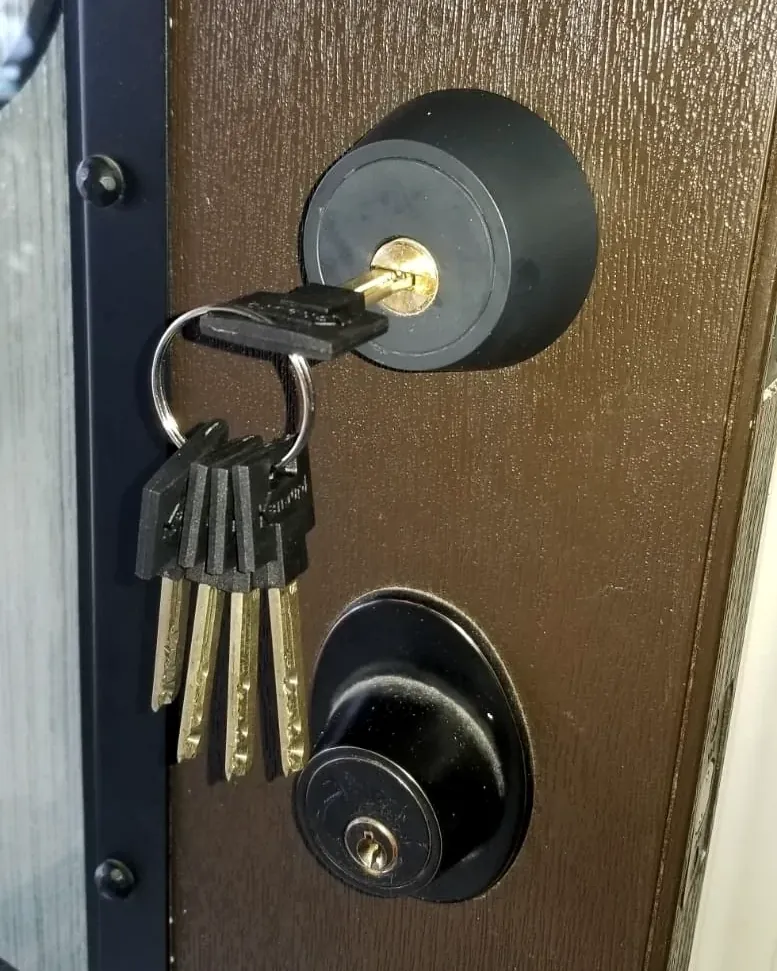 New keys hanging from a rekeyed deadbolt on an apartment door