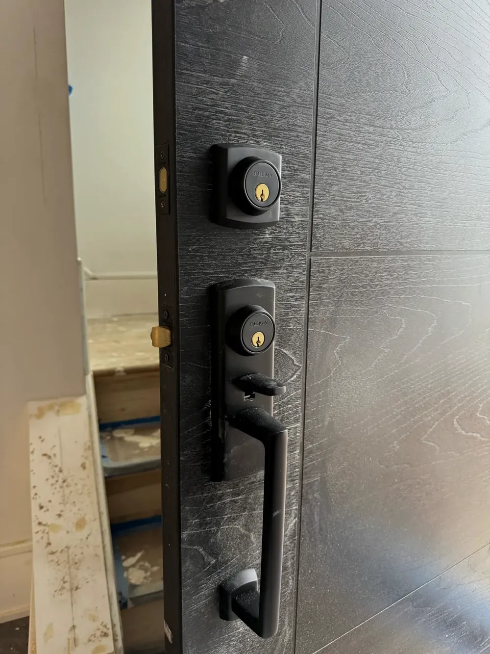Black handleset and deadbolt on a dark front door