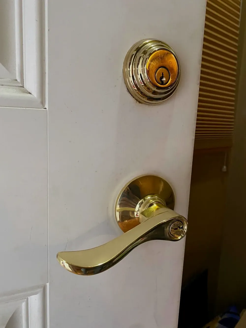 Brass deadbolt and lever handle on a white front door
