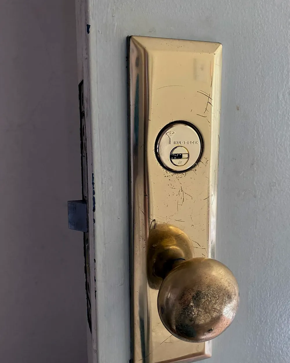 Brass mortise lock with a knob and key cylinder on a white front door