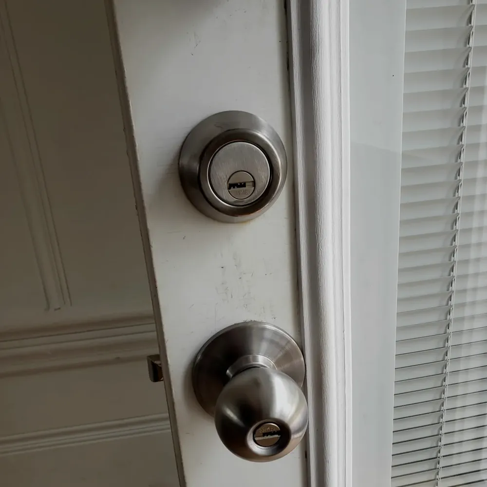 Deadbolt above a knob lock on a white entry door