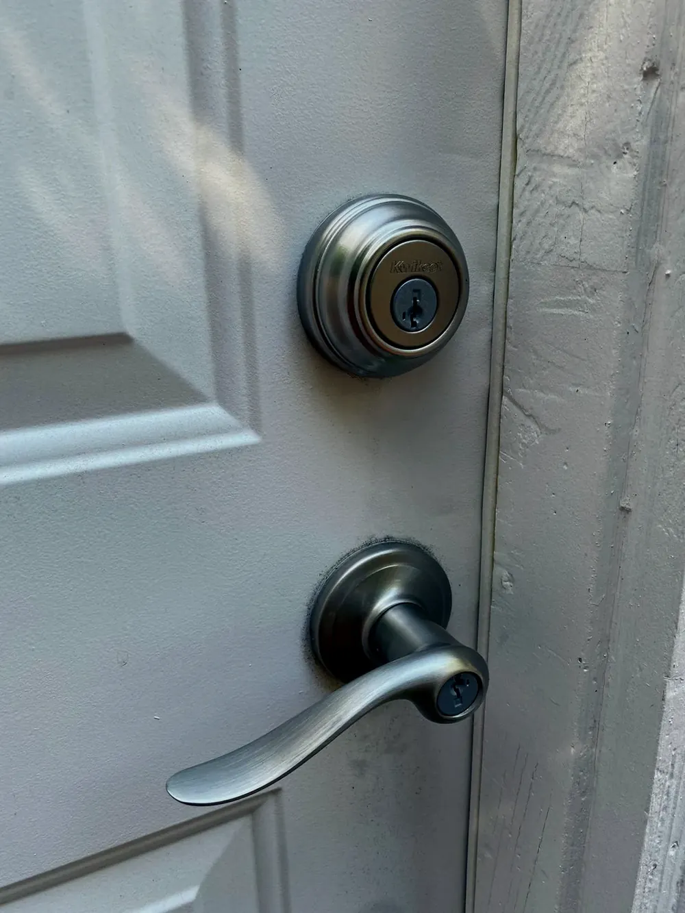 Deadbolt above a lever handle on a white door