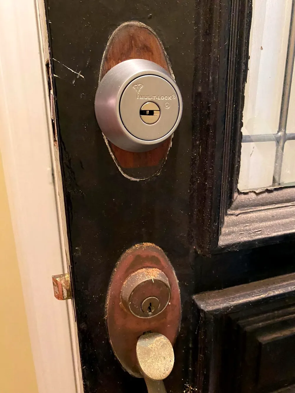 Deadbolt and lock cylinder on a weathered dark entry door