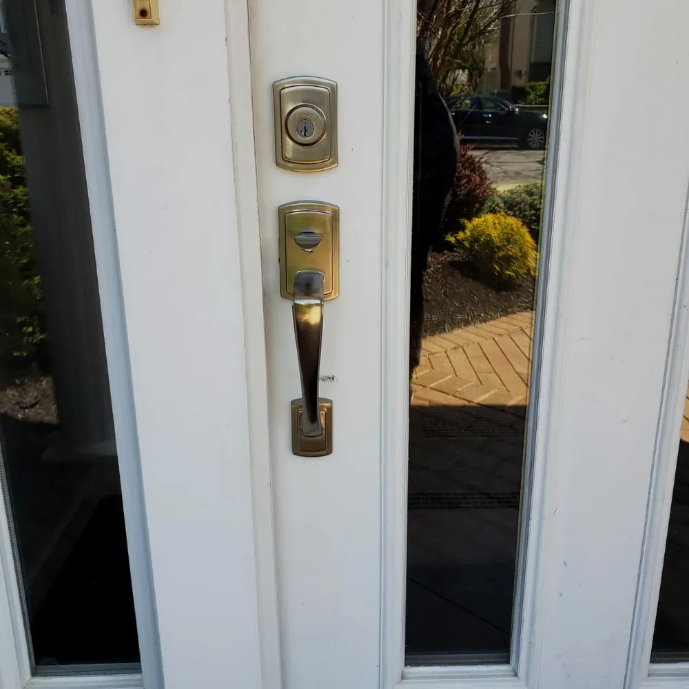 Handleset and deadbolt on a white front door with glass sidelights