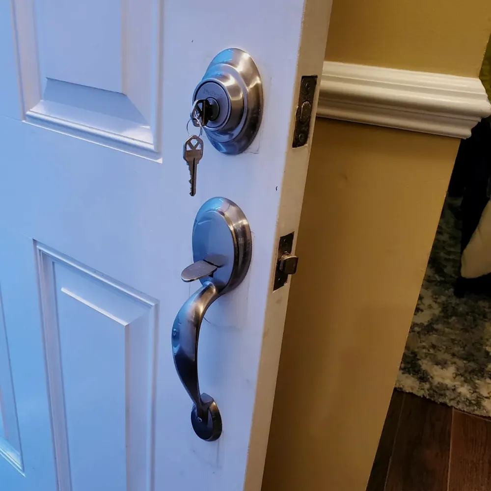 Deadbolt with keys and a handleset on a white door