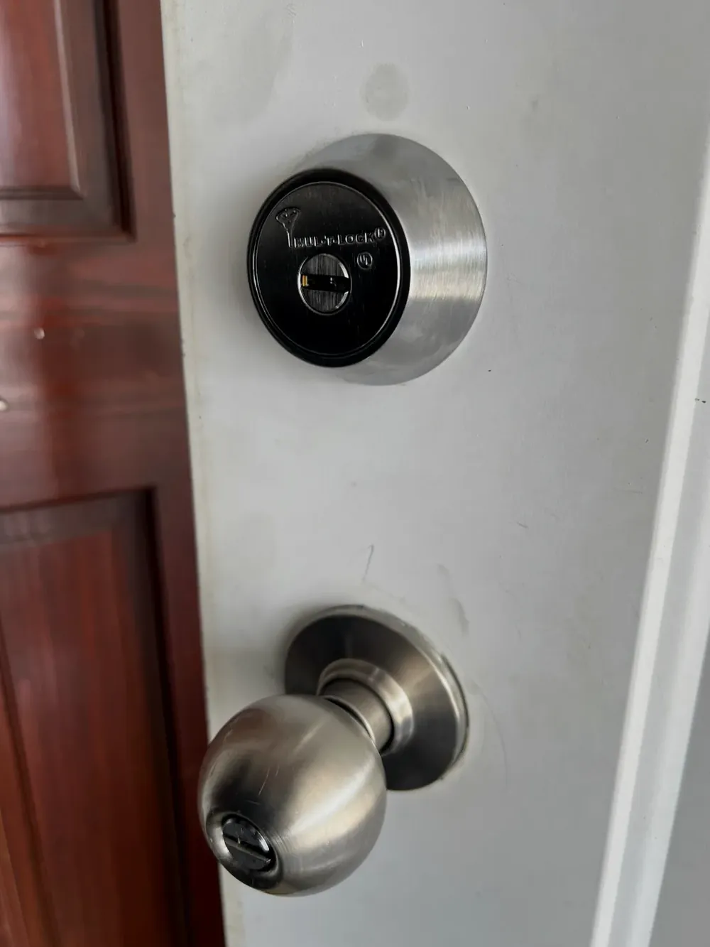 Deadbolt above a knob lock on a white entry door