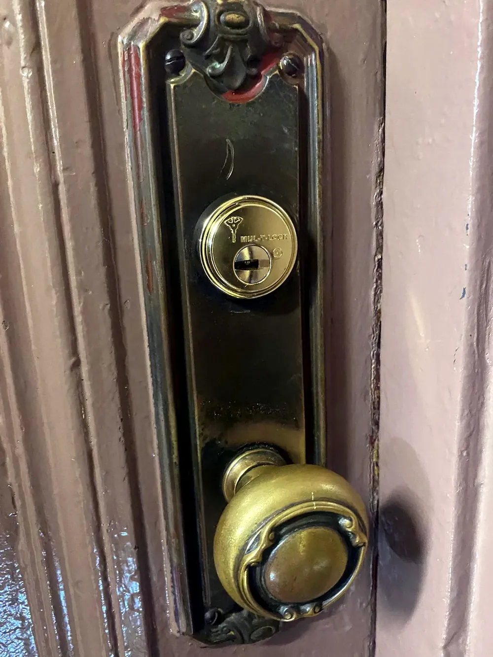 Original brass mortise lock with a knob and key cylinder on an older wood door