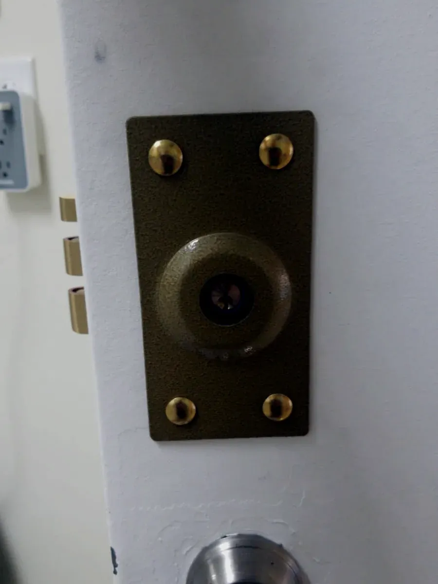 Brass deadlock with a key cylinder above a knob on a white door