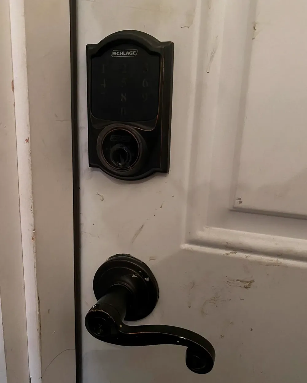 Schlage keypad deadbolt above a lever handle on a white entry door
