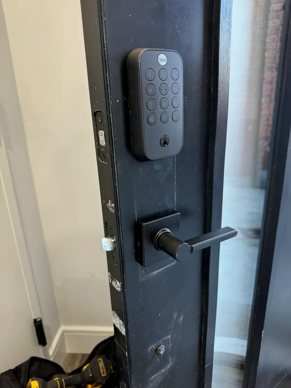 Keypad smart lock above a lever handle on a dark apartment door