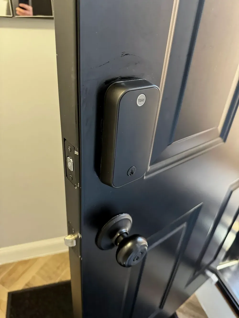 Black keypad smart lock above a knob on a dark entry door