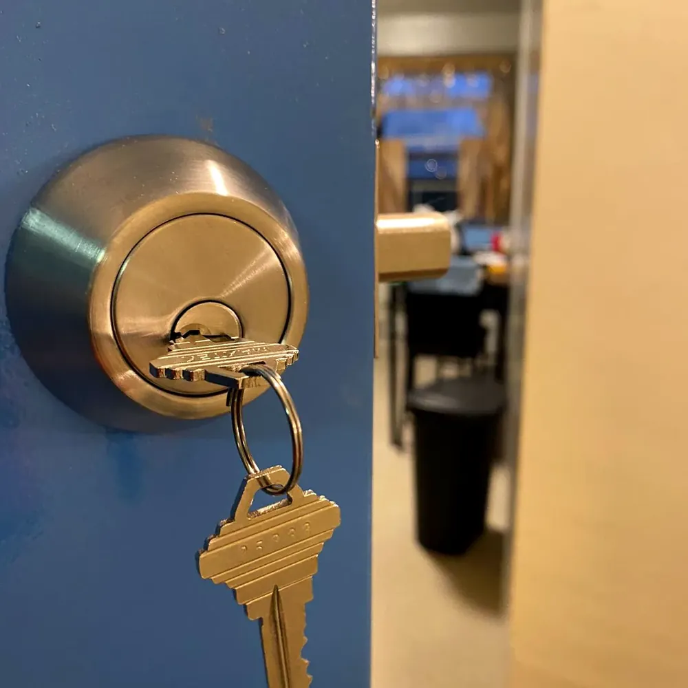 New key in a brass deadbolt on a blue door