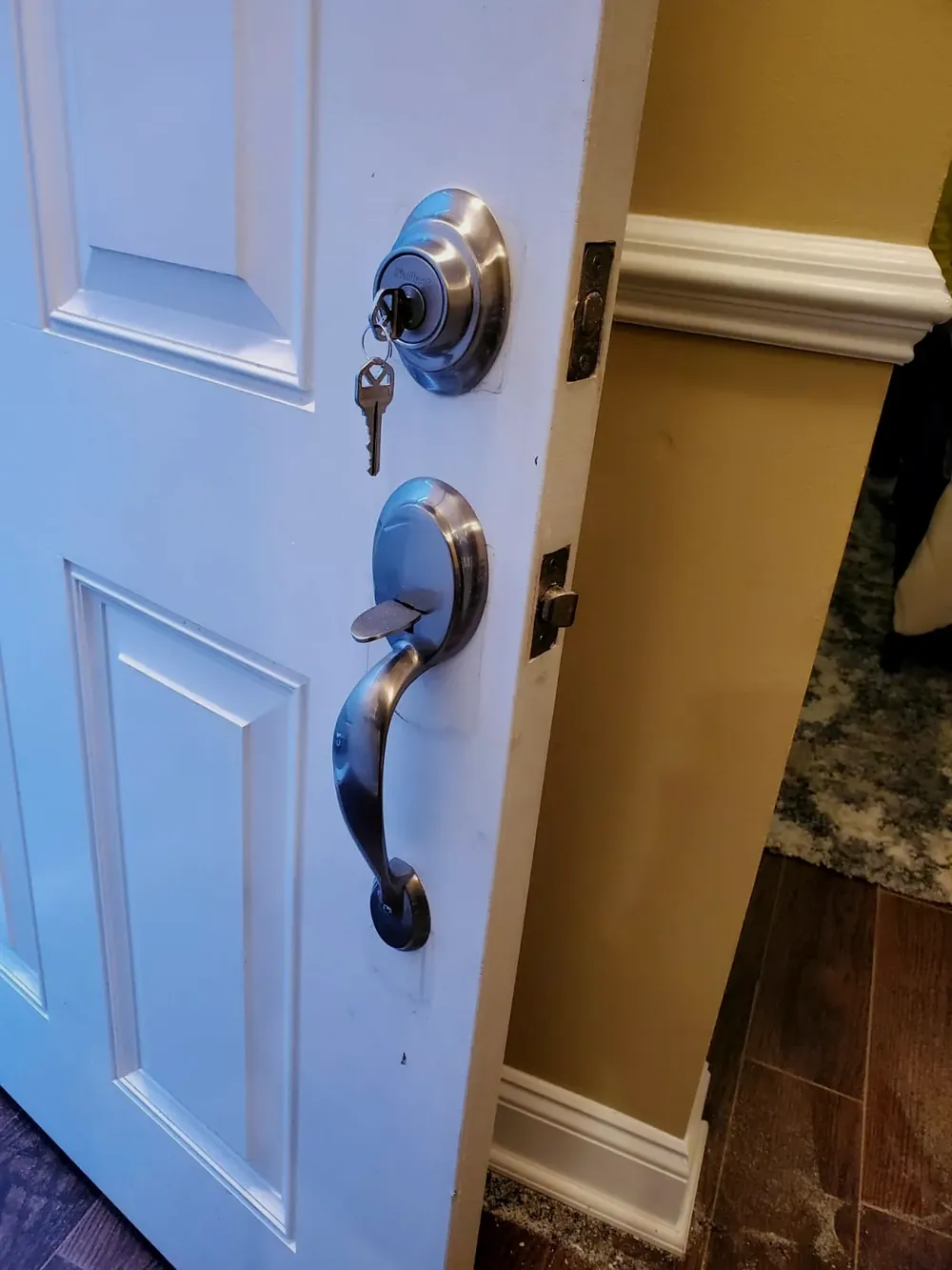 New handleset and deadbolt with a key on a white front door
