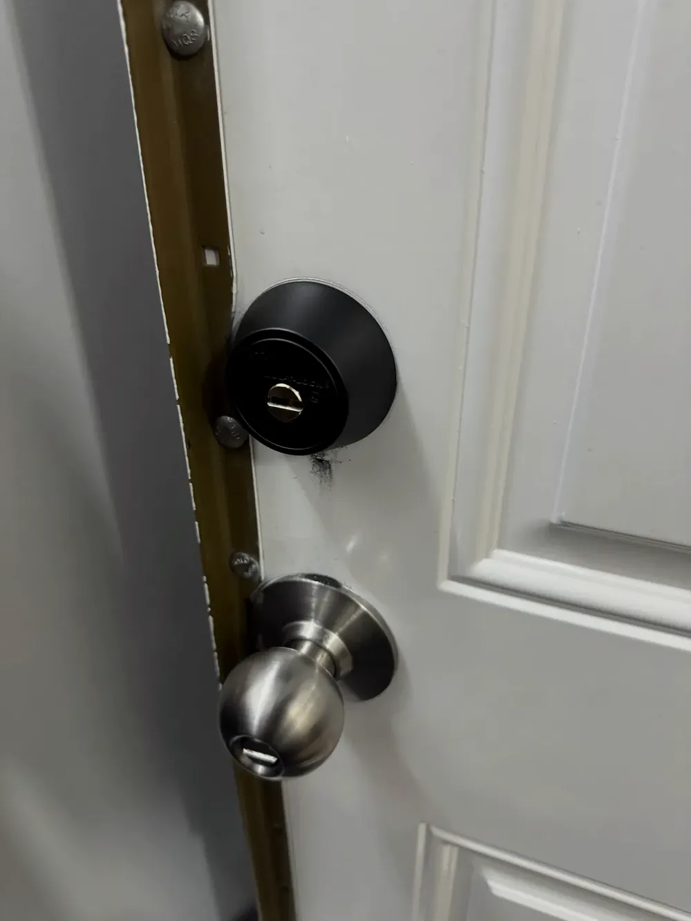 Black deadbolt above a knob lock on a white entry door