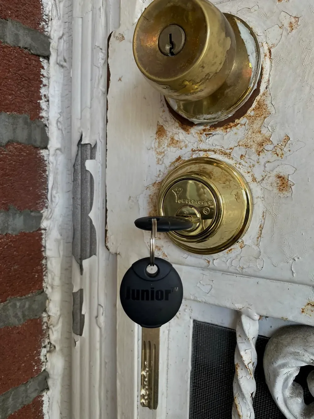 Corroded brass knob lock and deadbolt on a weathered door